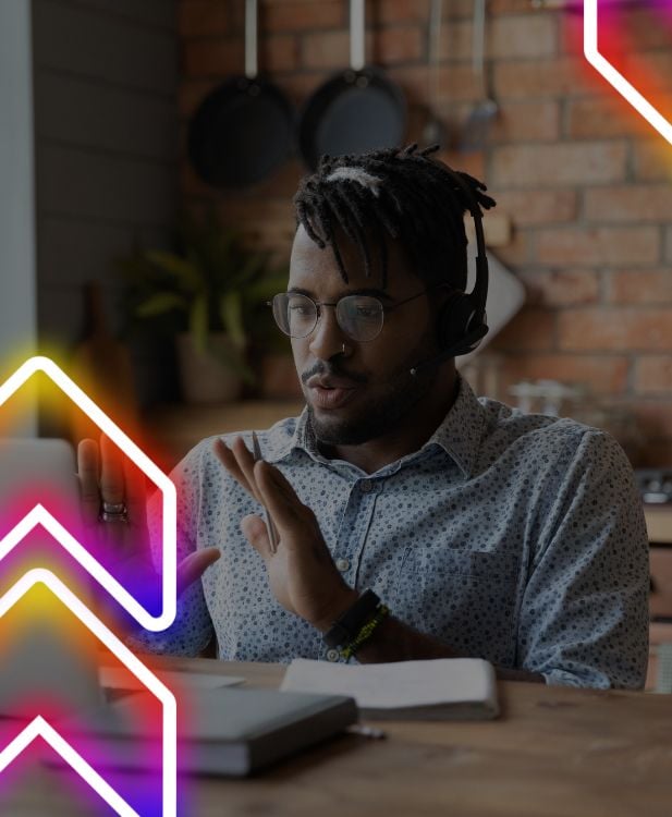 Young Black customer service representative talks through a solution on a call while sitting on his laptop at home