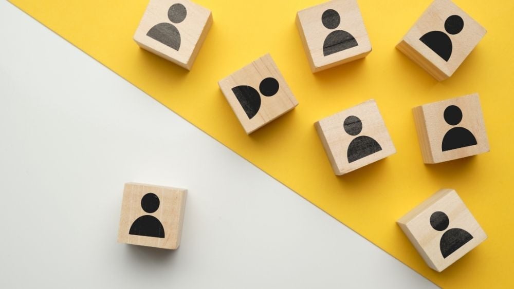 Scrabble blocks with person icons painted on them, one is separated from the rest