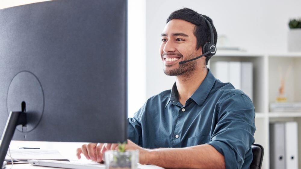 Customer service representative smiles at monitor while serving a customer