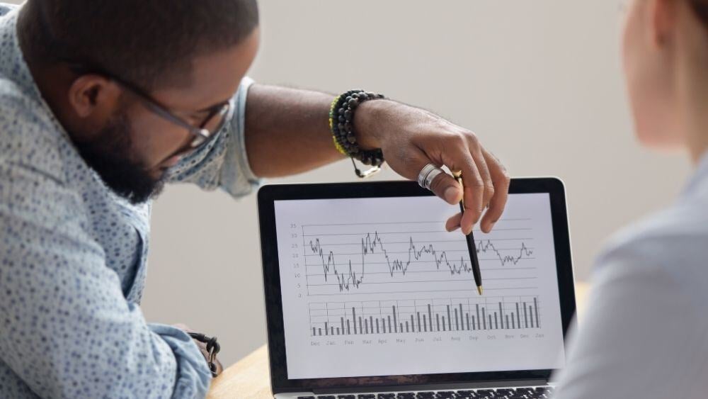 Corporate individual points to laptop screen with year over year data