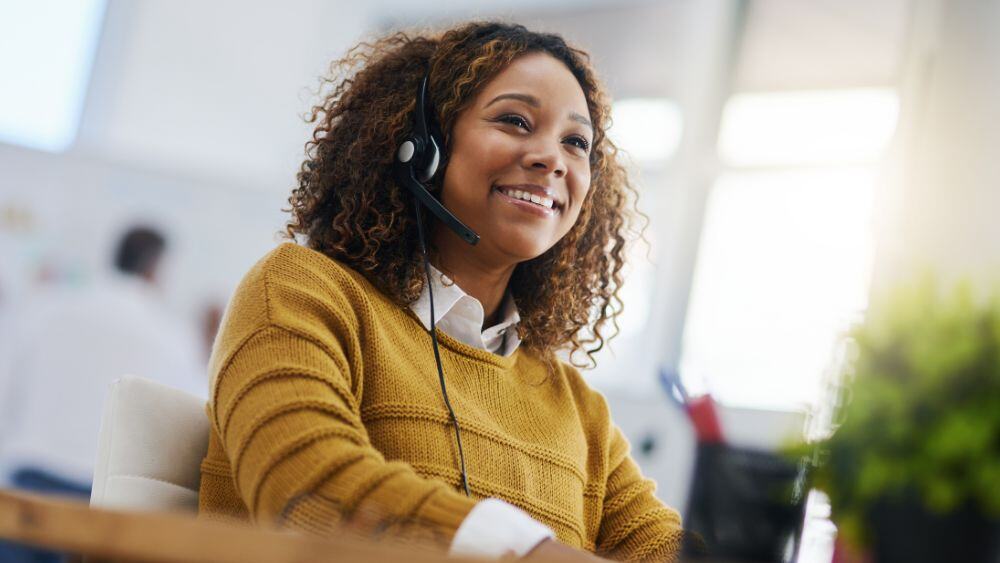 Competent and joyful customer service agent takes a call via headset in home environment