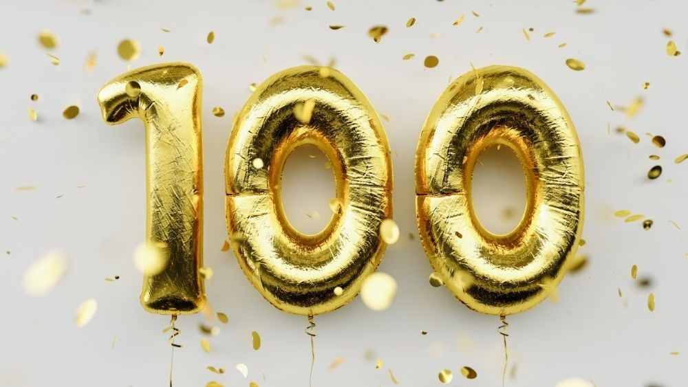 Three balloons spell out the number 100 in a celebratory gold style