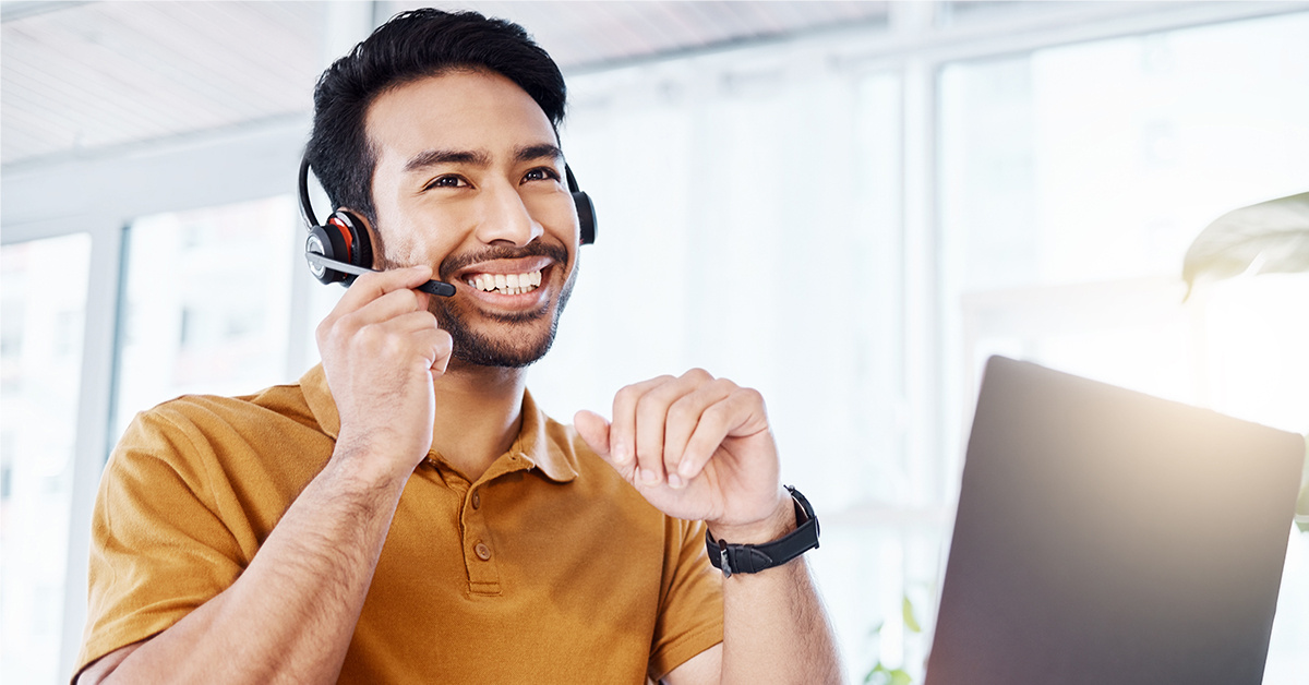 Working Solution Agent holding a headset while working on the computer