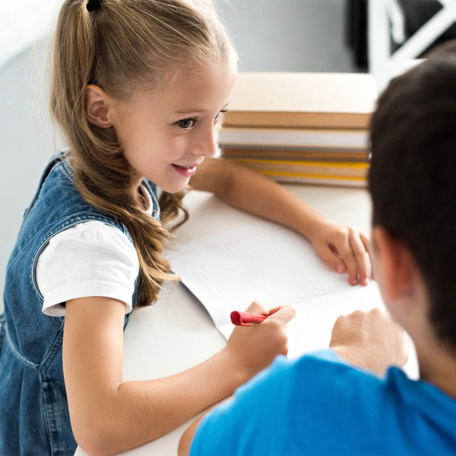Girl writing in paper while looking at another person