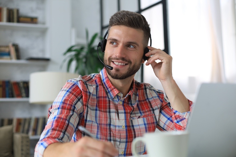 Competent customer service representative smiling and taking notes